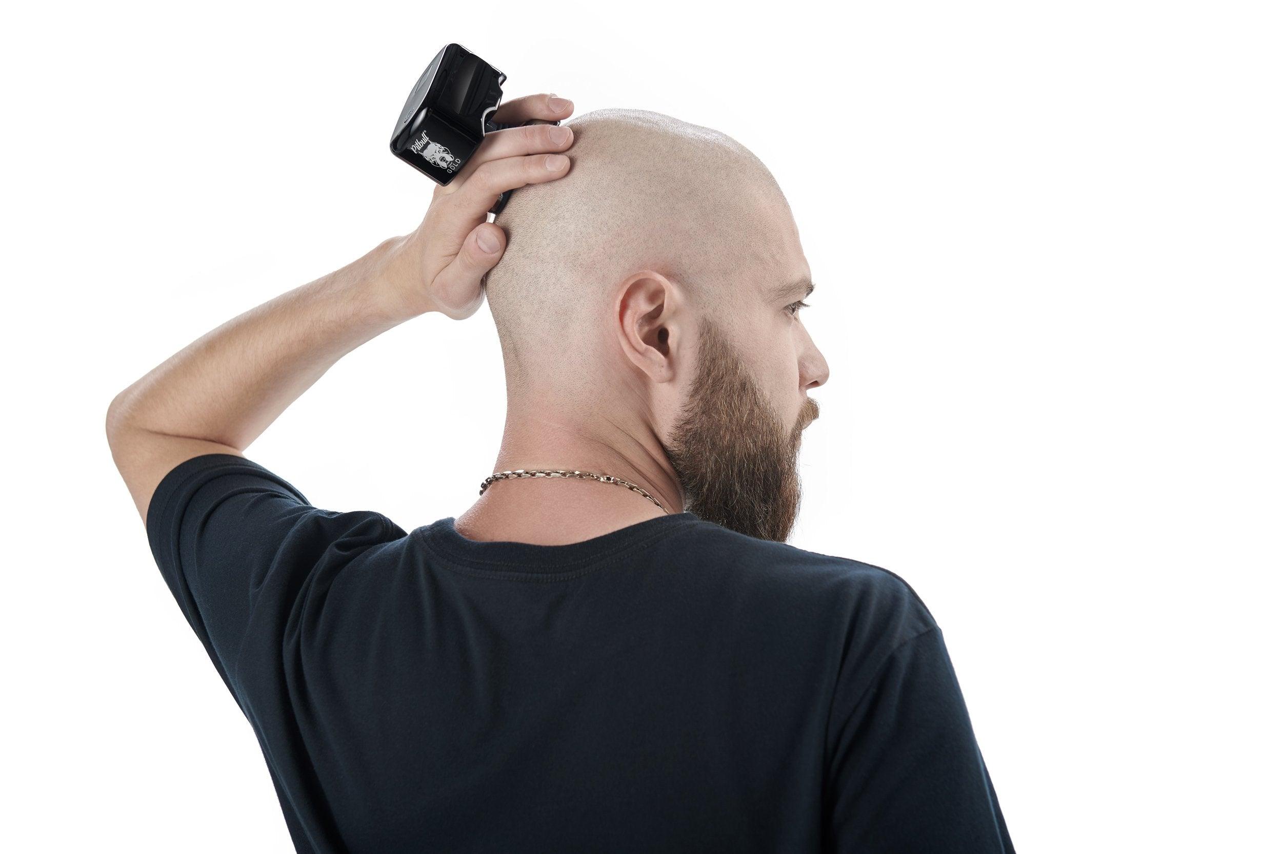 shaved head look - a man shaving his bald head with an electric shaver by himself